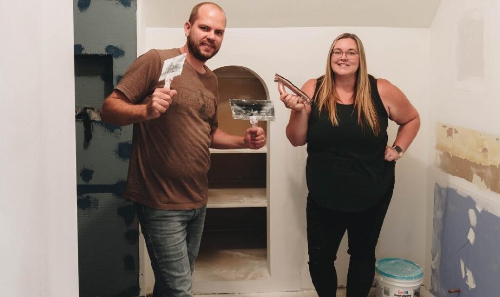 two people holding painting supplies in their hand, about to start painting a bathroom