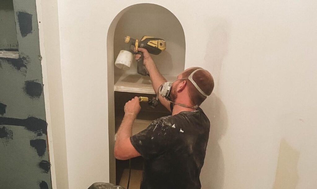 person painting inside of a cabinet in the bathroom