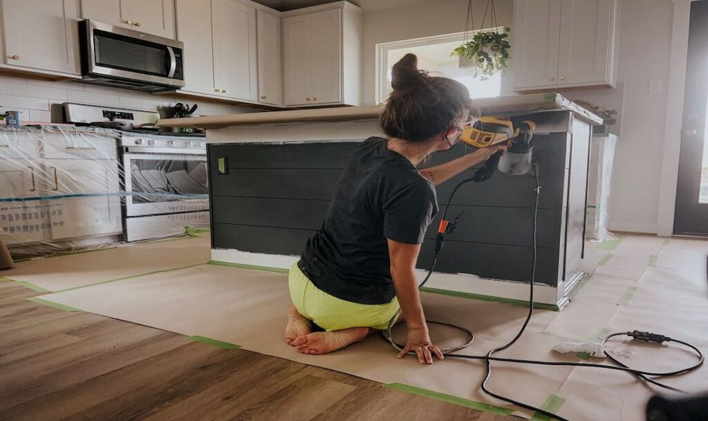 person spraying a kitchen island with a paint sprayer