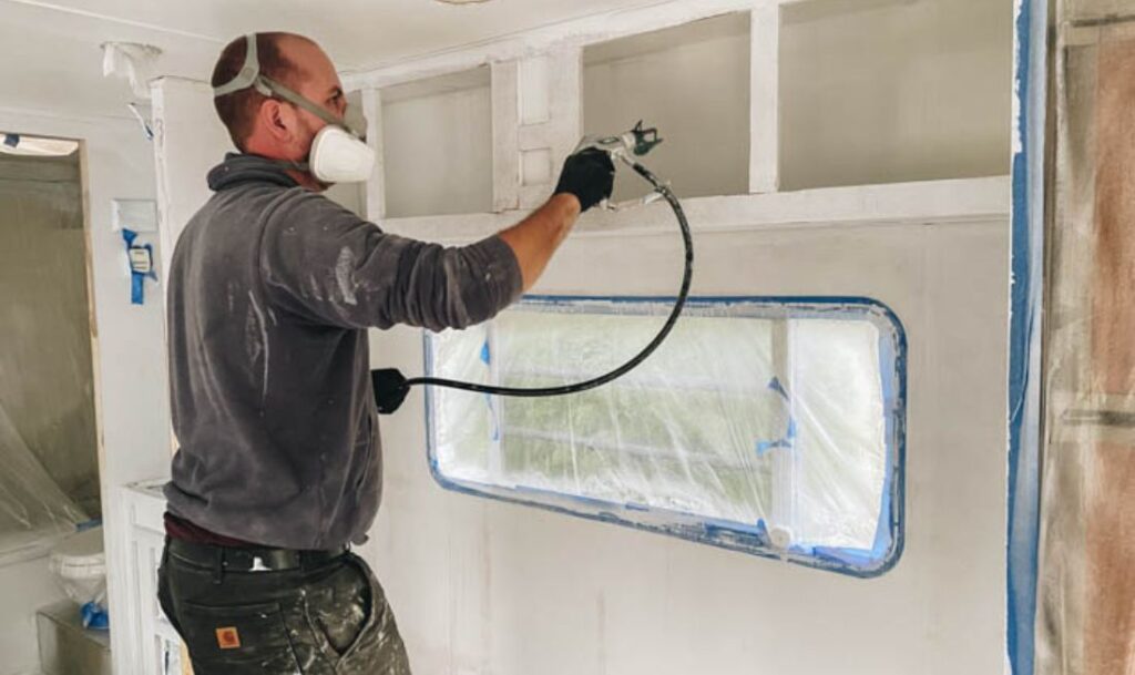 person spraying paint inside of RV above a window with the Wagner Control Pro HEA 170
