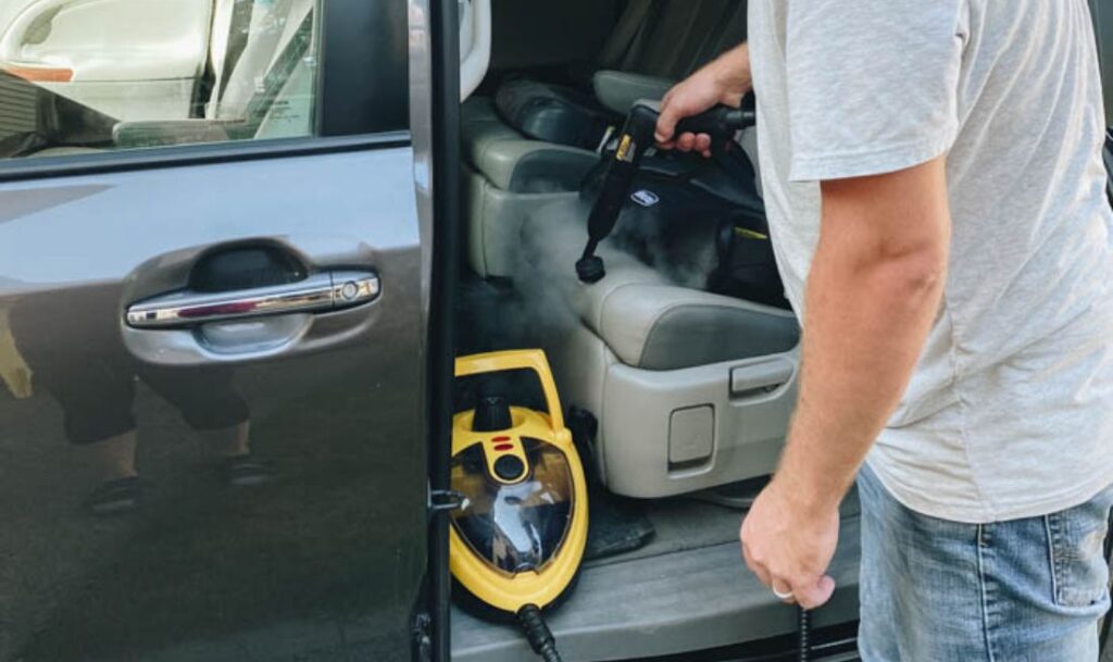 man detailing and steaming the inside of his car with a 915e Steamer handheld attachment