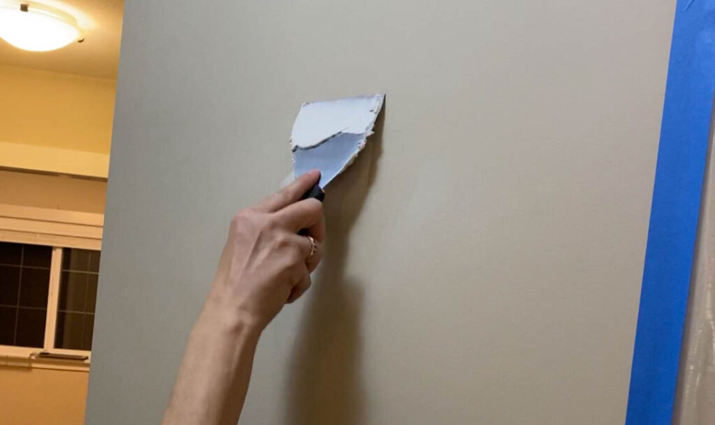 filling in holes on wall with putty and a scraper