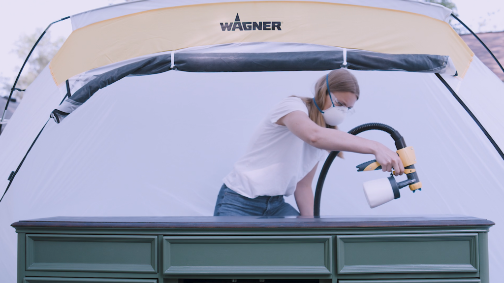 woman spraying furniture inside a spray shelter