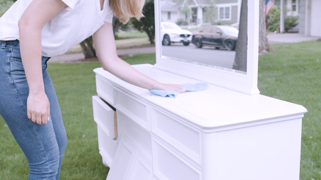 woman sanding down a dresser and cleaning