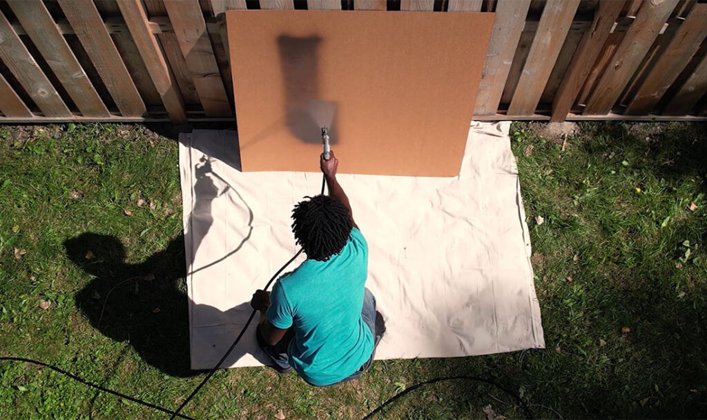 practicing spray pattern on piece of cardboard