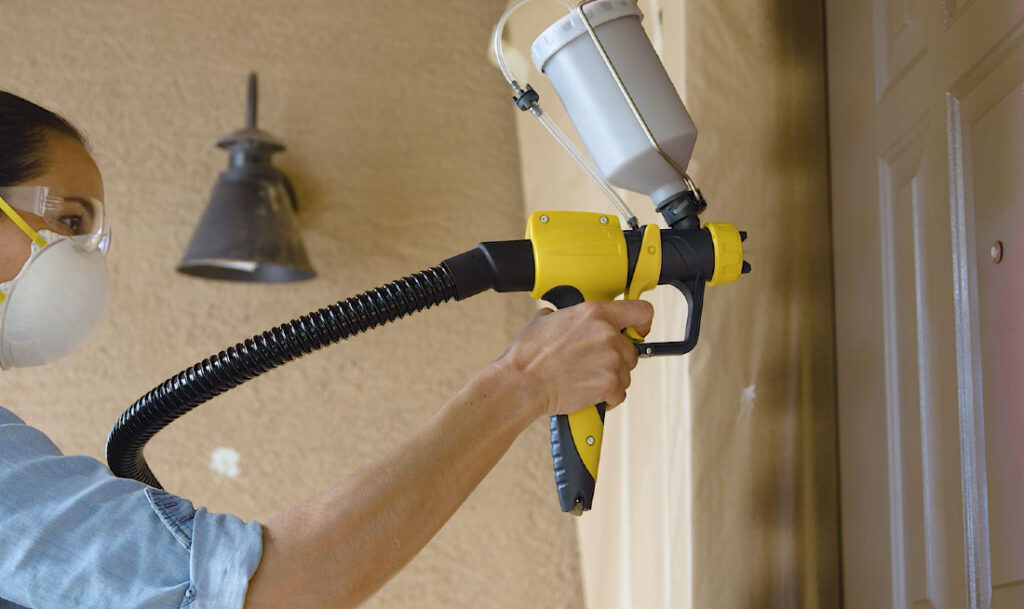 close up of spraying a front door with a paint sprayer